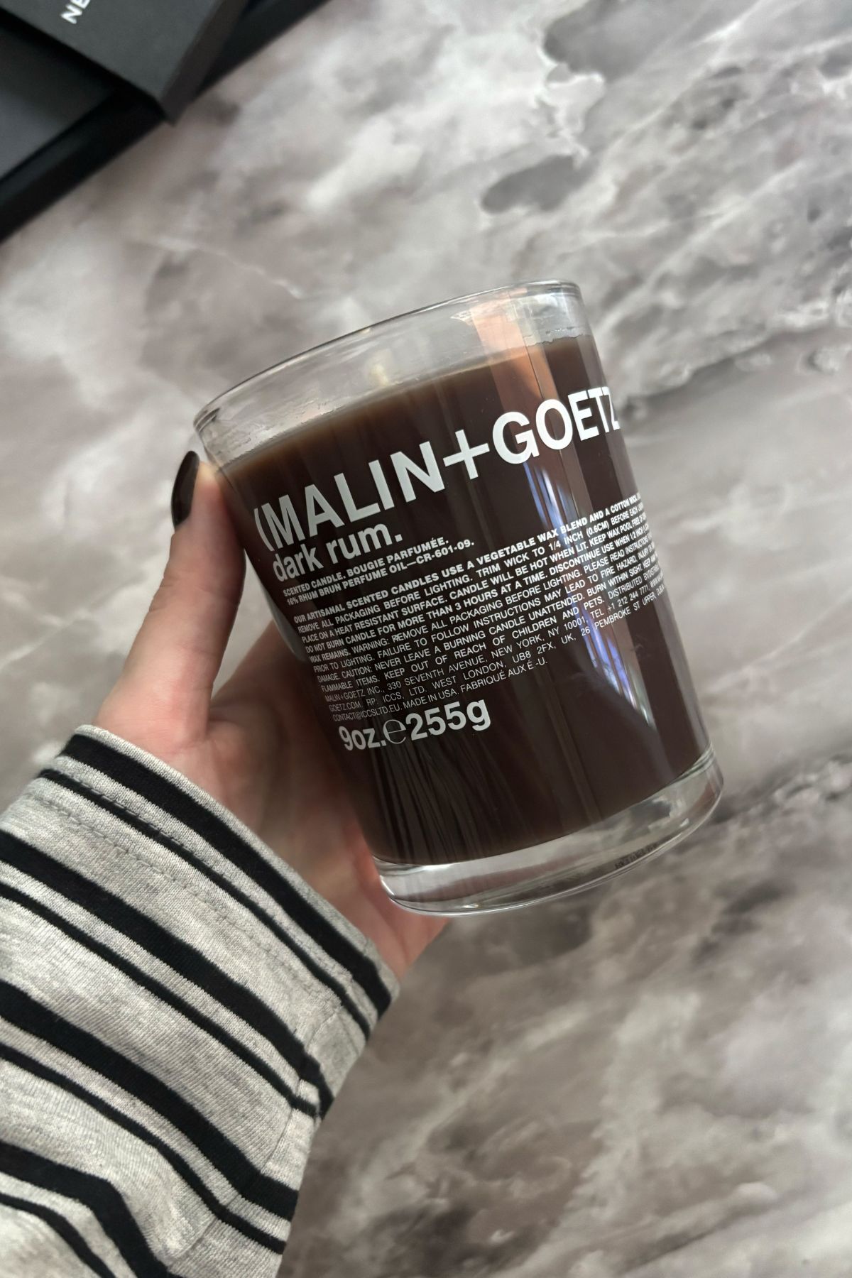 Deputy beauty editor Grace Lindsay holding the Malin + Goetz Dark Rum candle