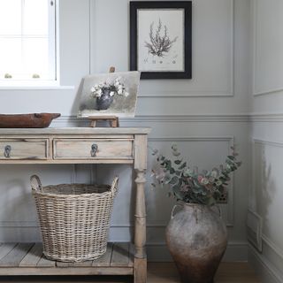 A rustic-style sideboard displaying a vintage artwork and a wicker storage basket