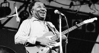 Blues legend Muddy Waters plays his red Fender Telecaster, capo'd at the 3rd fret, onstage in Central Park, NYC, circa 1978.