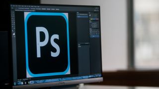 The Photoshop software and logo is displayed on a computer monitor