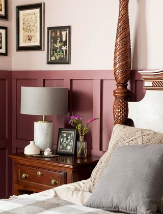 traditional bedroom with pink panelling, lamp shade, four poster wooden bed and black picture frames with flowers