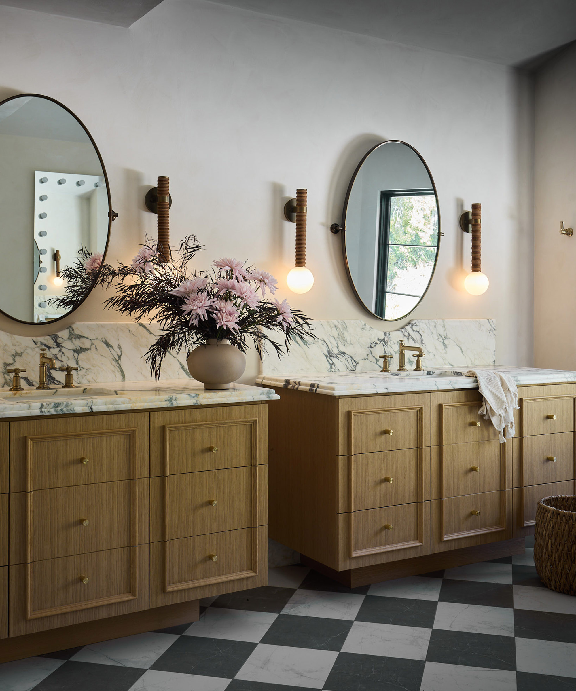 large bathroom with double vanity, checkerboard floor and round mirrors above each basin