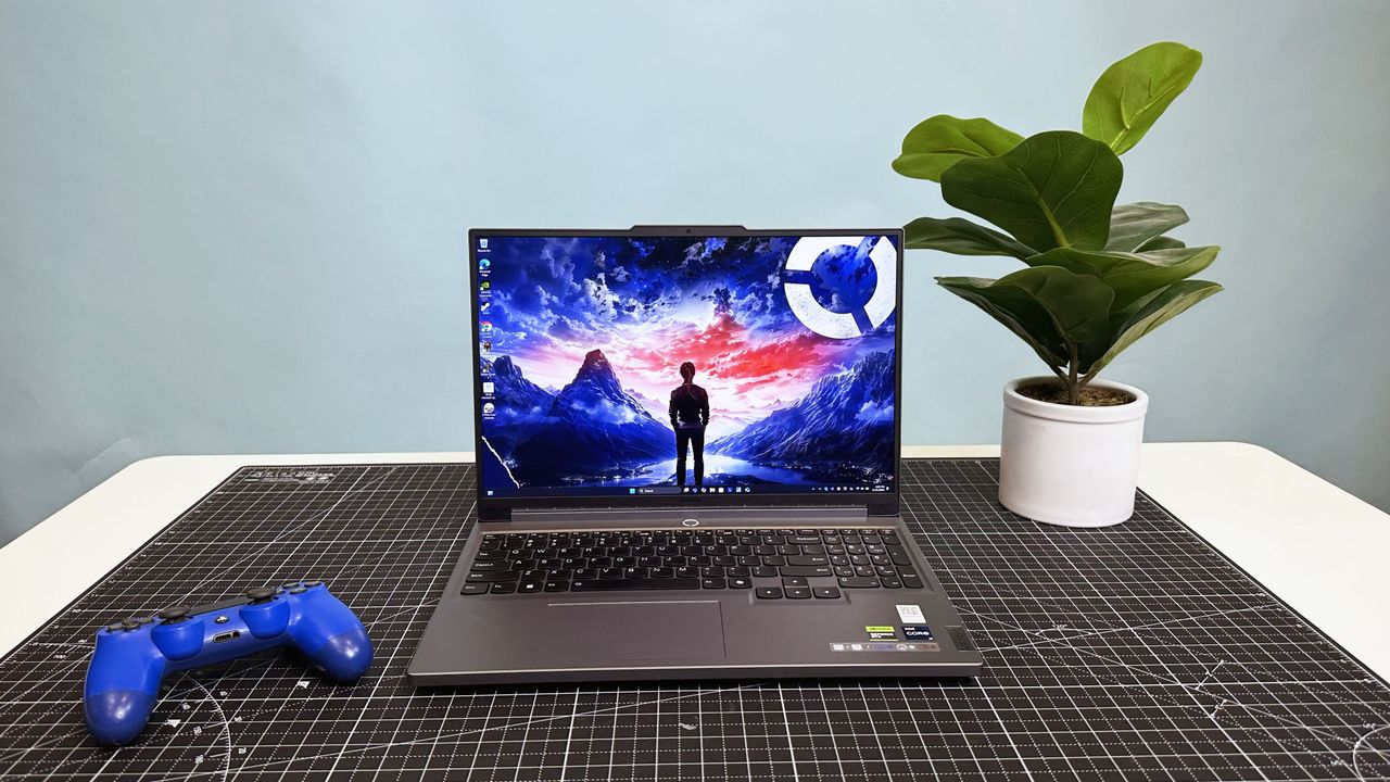 Lenovo Legion 5i Gen 9 16-inch with lid open on a gray desk mat beside a potted plant and a game controller