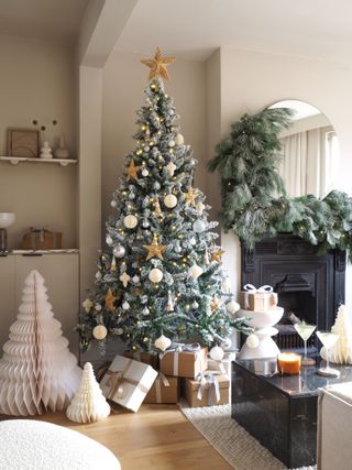 a neutral flocked christmas tree and garland wrapped around a mirror