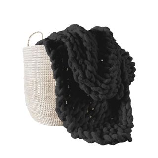A black knitted blanket inside a white basket