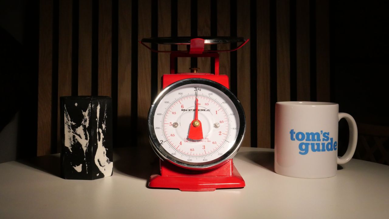 A photo of a set of red scales next to a Tom's Guide Mug.