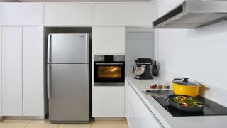 A refrigerator with cabinets above it