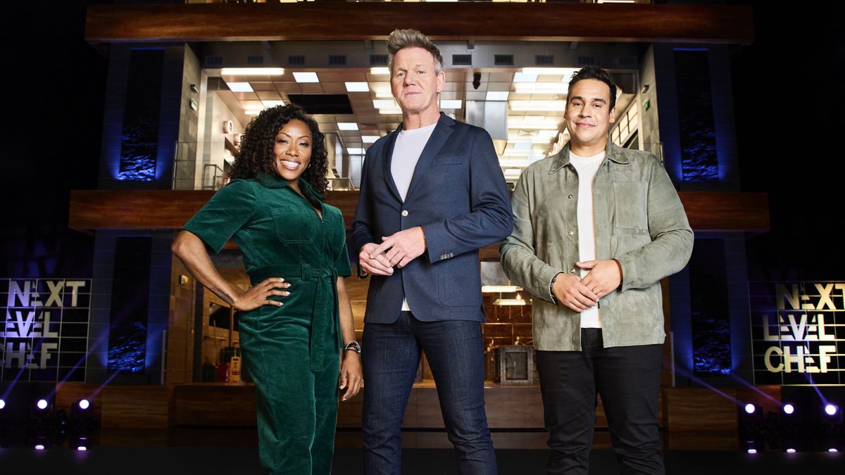 Nyesha Arrington in a green jumpsuit, Gordon Ramsay in a blue jacket and jeans and Paul Ainsworth in a grey top and dark trousers stand in from of the towing kitchen in Next Level Chef.