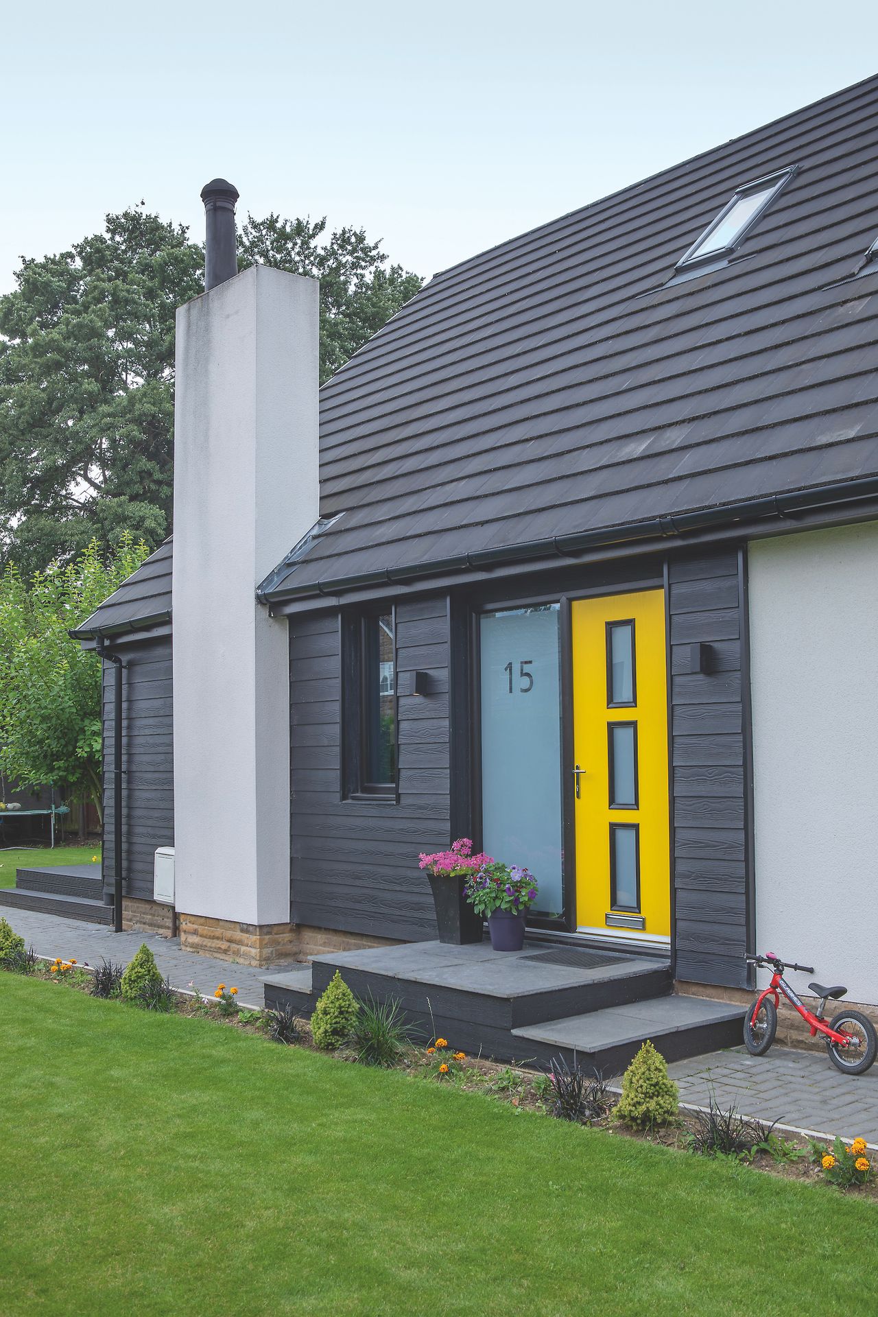 black cladding on house with yellow front door and white render