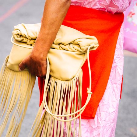 yellow leather fringe bag with orange sweater and pink skirt