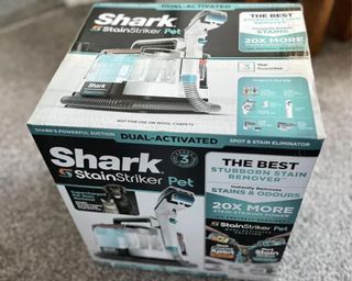 Shark StainStriker in box on grey living room carpet