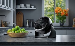 Honeywell desk fan on kitchen table beside bowl of apples
