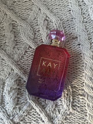 Kayali Fleur Majesty Rose Royale perfume bottle laying on grey blanket