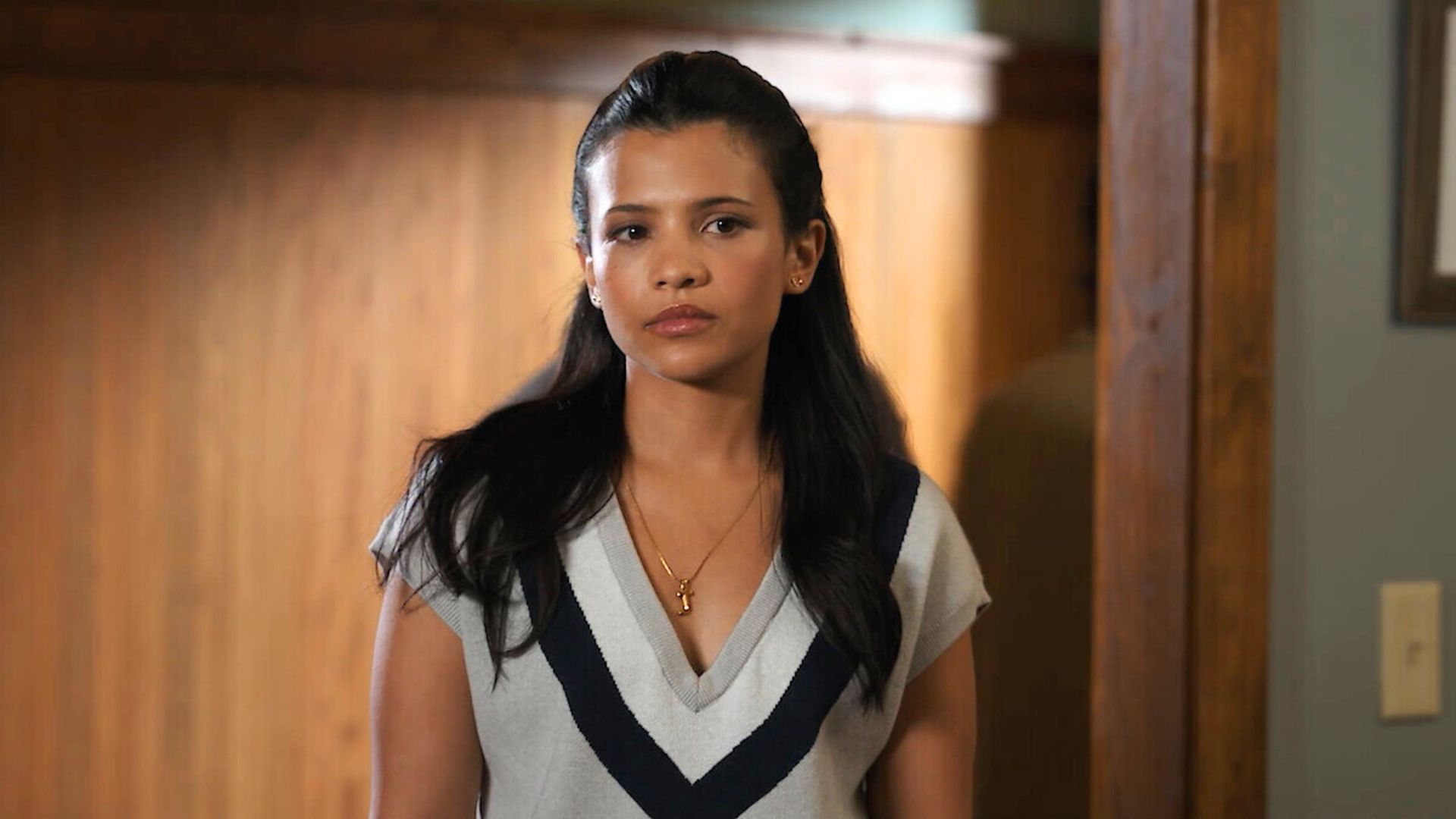 Jackie stands in a doorway looking serious