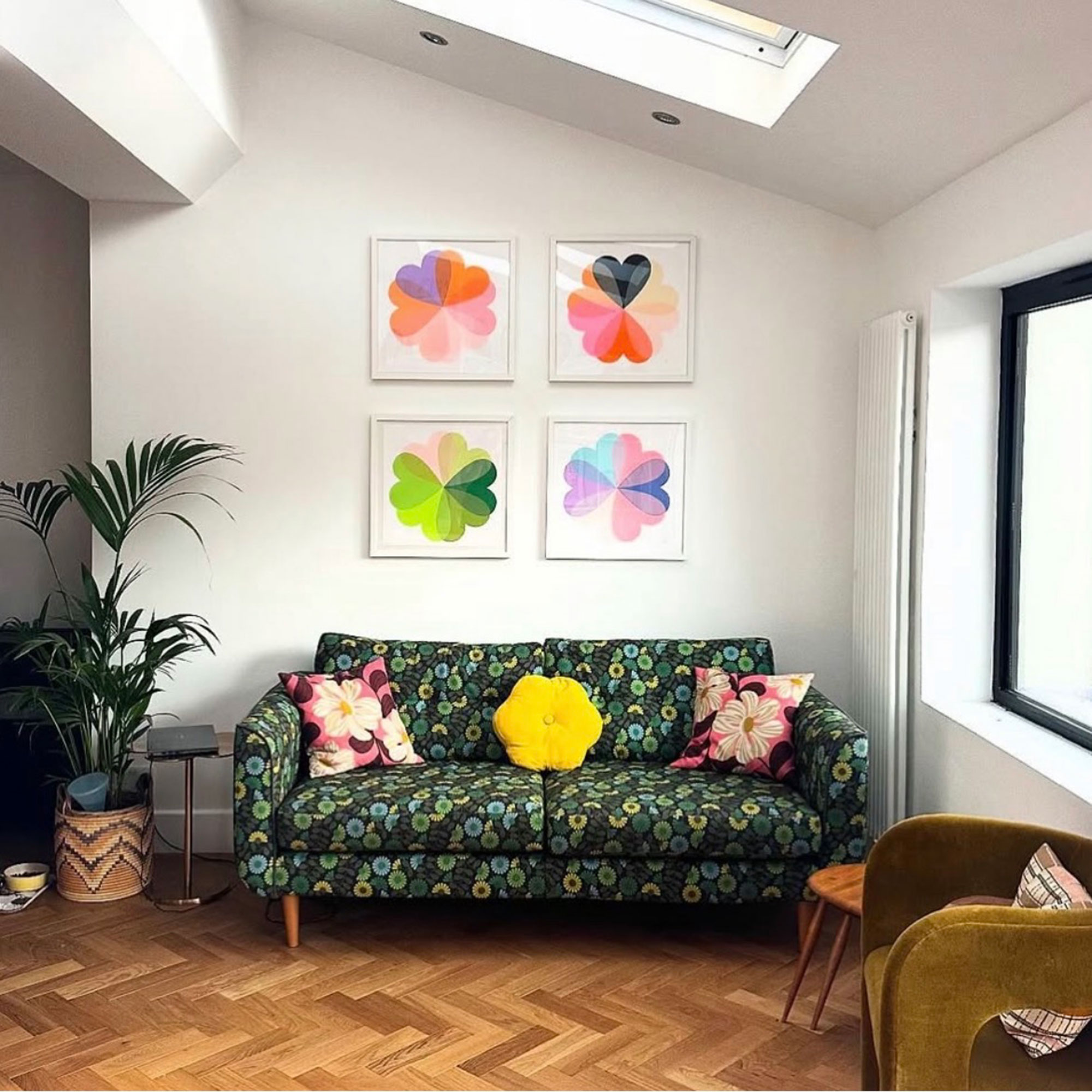 Living room with four colourful graphic art prints above green floral sofa