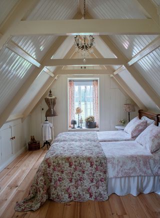 attic bedroom with steep pitched roof paneled walls and ceiling twin beds with floral covers