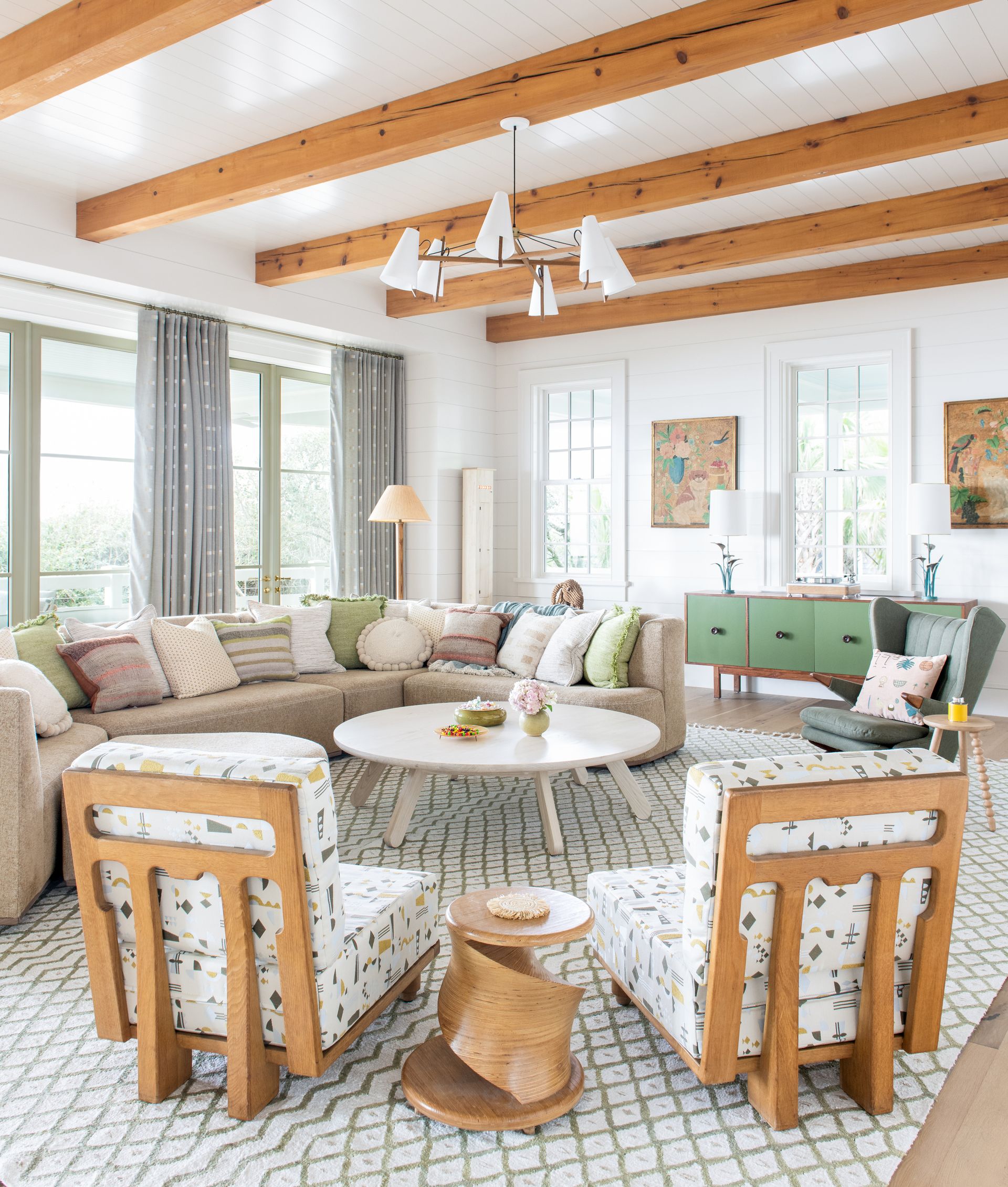 Green themes throughout the living room with green window frames, pillows, cabinet, vases and hints of green in paintings