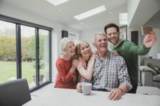 A multigenerational family takes a selfie in the kitchen.
