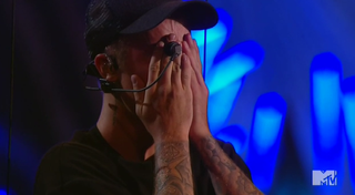 Justin Bieber with his hands over his face as if crying.