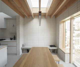 A kitchen with a wooden table and white tiled walls