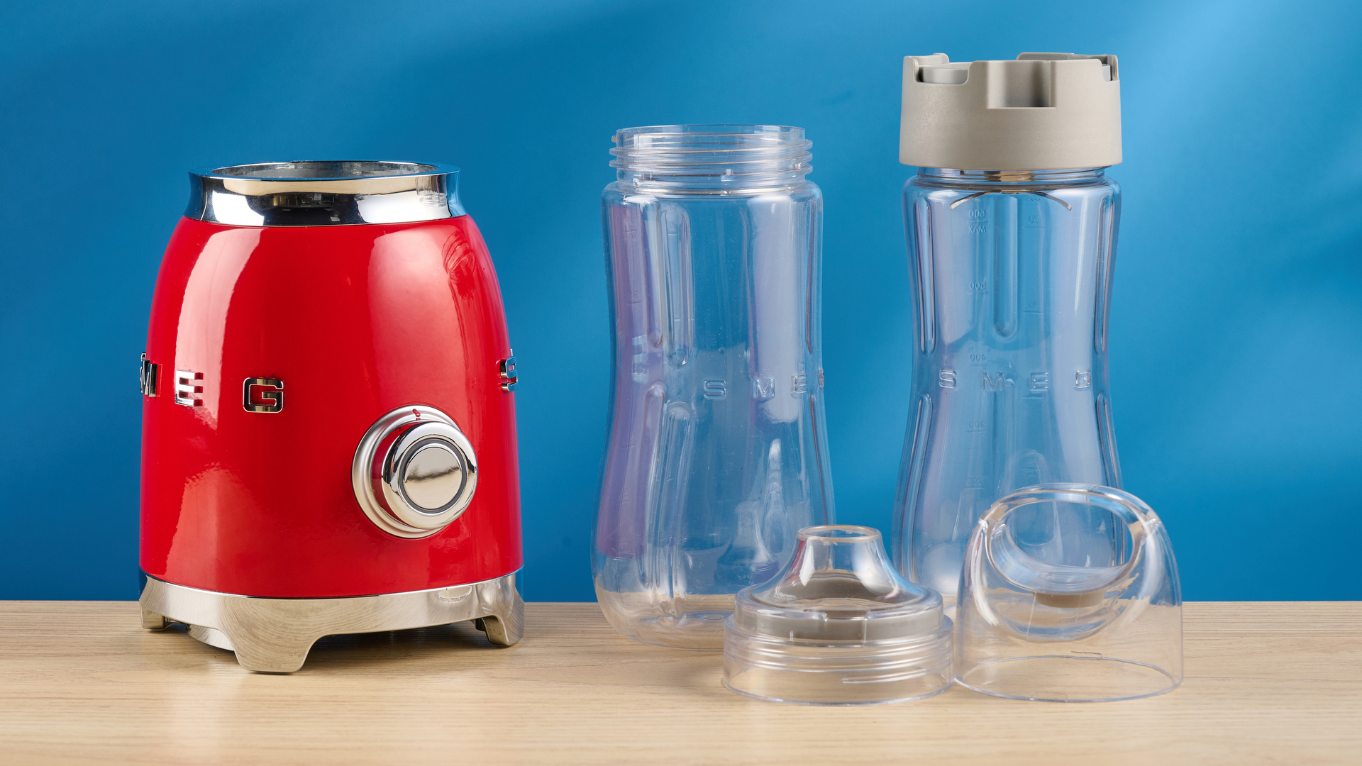 Smeg Personal Blender in the red colorways photographed in front of a blue background.