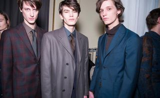 3 male models in suit jackets look towards the camera