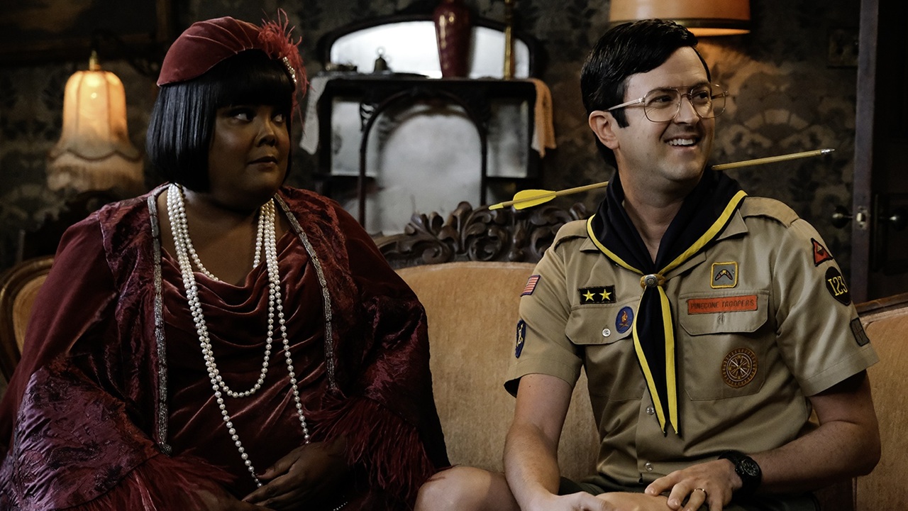 Romance blossoms between lounge singer Alberta (Danielle Pinnock) and youth group leader Pete (Richie Moriarty) as they sit knee-to-knee on an ornate sofa in Woodstone Manor's living room for Ghosts season 5.