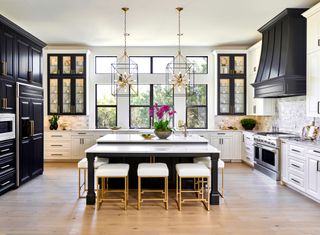 Large kitchen with dark and white cabinetry, central island, pendant lights and wood floor
