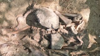 Big stones on top of human skeleton remains.