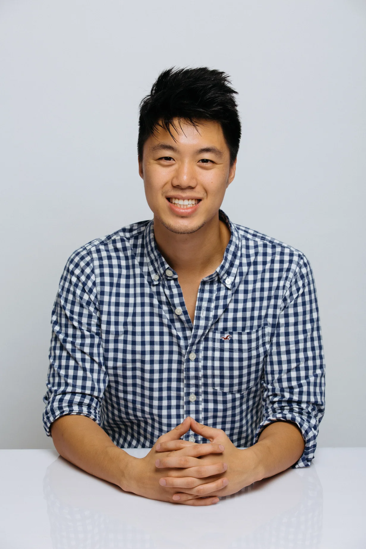 A headshot of a man in checkered shirt smiling at a camera