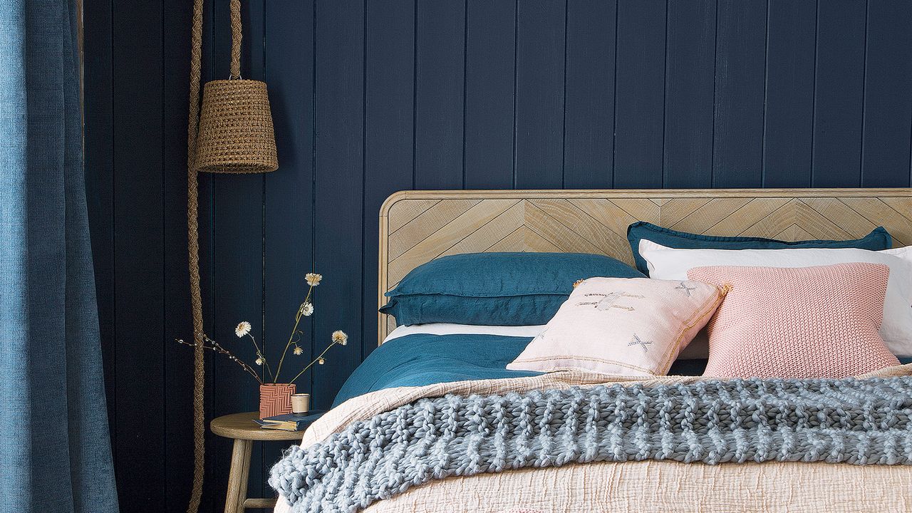 A navy bedroom with a wooden bed and pink accessories