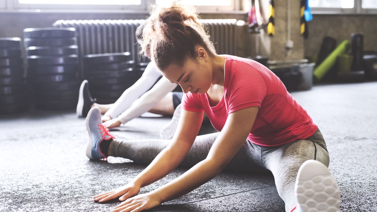 Two you women doing flexibility exercises in gym