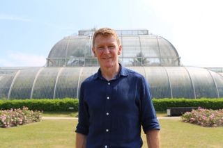 Tim Peake photographed in front of a large greenhouse in Kew Gardens.