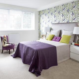 bedroom with floral wallpaper and purple armchair and grey headboard