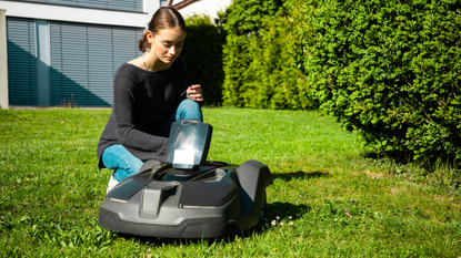 Best robot lawn mower: image depicts woman starting up robot mower on lawn
