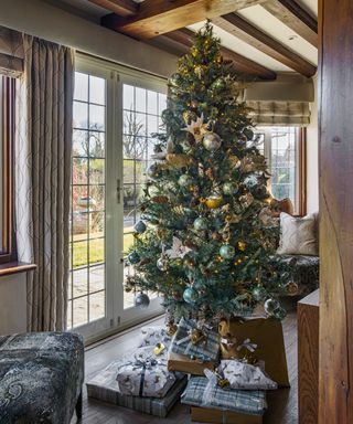 Christmas tree themes 2021 with green and gold decorations in a farmhouse with beams and views of the countryside