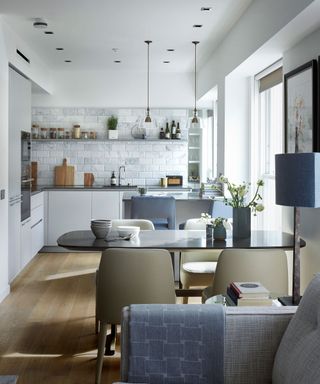 Small kitchen with white cabinets, dining table and chairs and sofa beyond