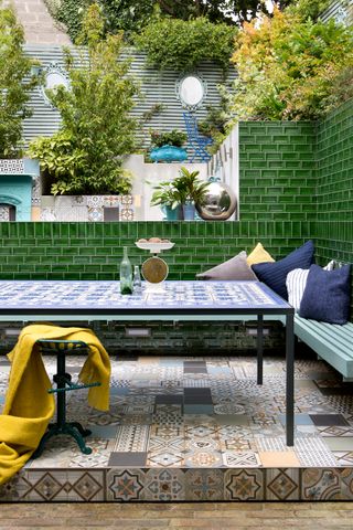 patio garden with tiled wall and bench with cushions