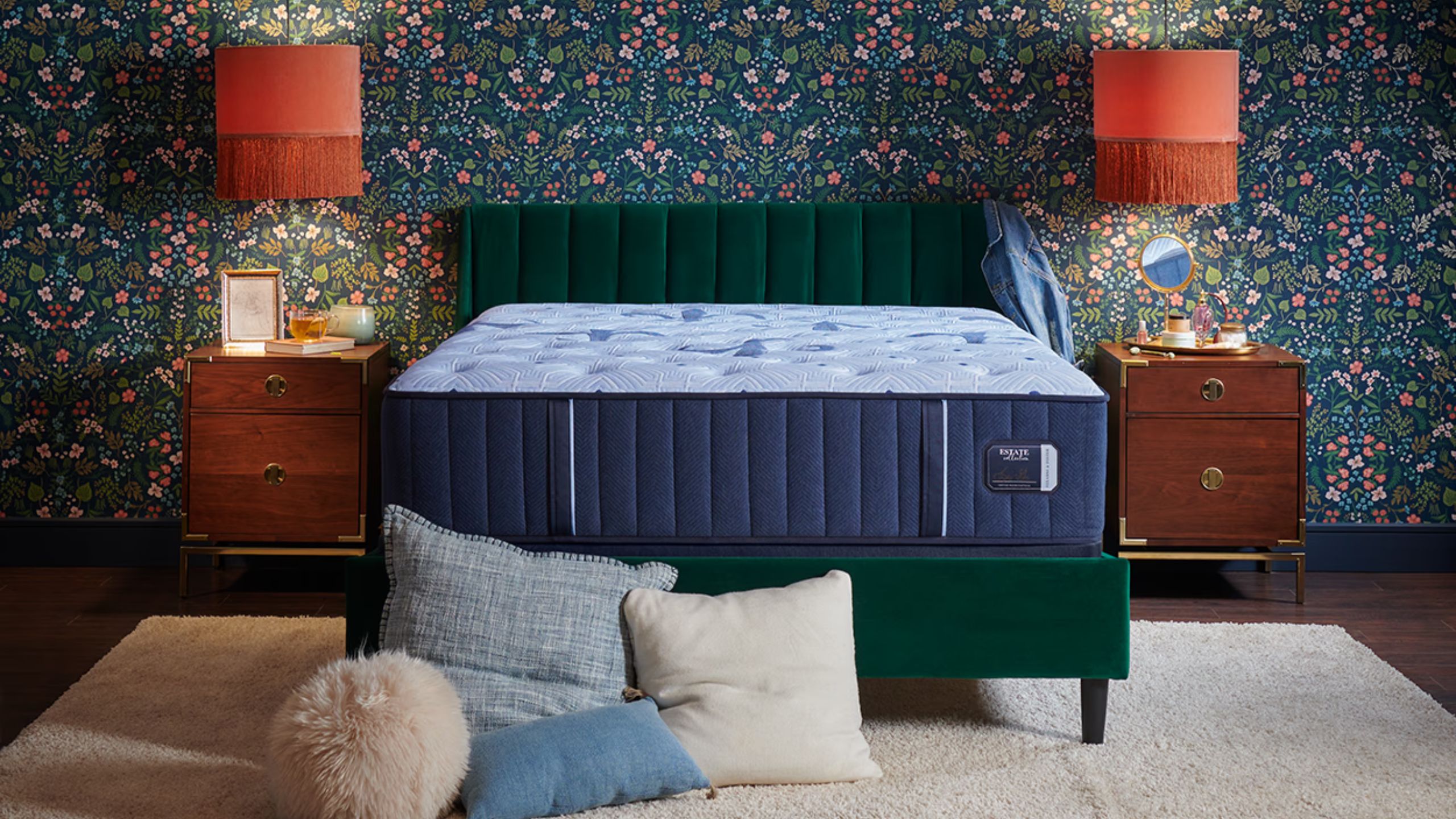 Stearns &amp; Foster Estate Mattress on a dark velvet bedframe in a bedroom with blue floral wallpaper, orange lamps, and matching dark wood bedside tables