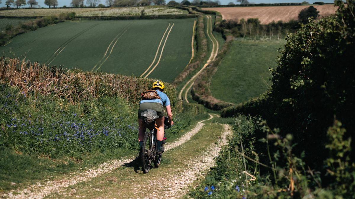 A white female gravel cyclist descends some gravel doubletrack