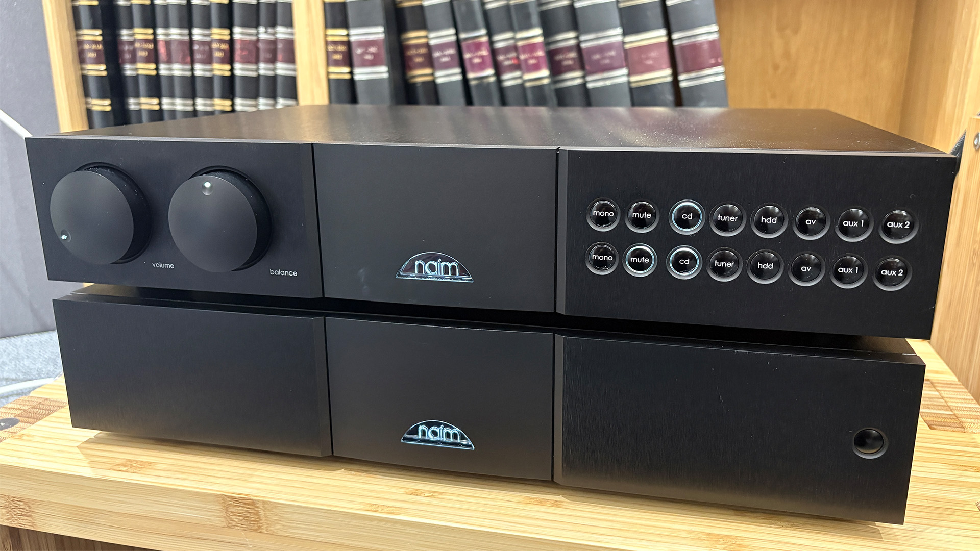 Naim NAC 552 / NAP 500 DR pre/power amplifier on wooden hi-fi rack in front of bookcase