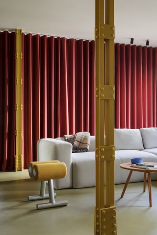 living room with pollen yellow metal columns and red curtain