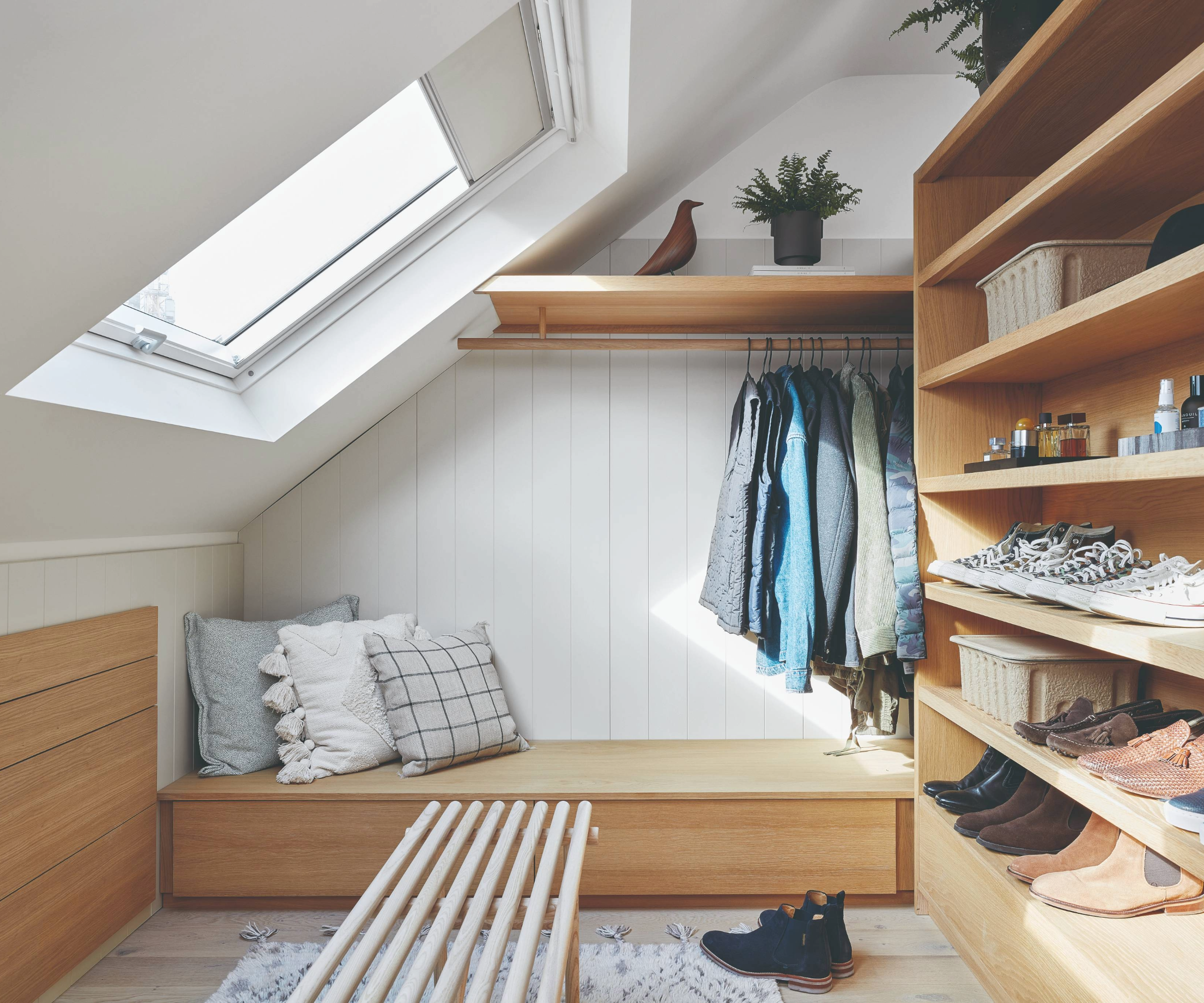 Loft used as a dressing room, with shelving for shoes, a bench with cushions, and a rail to hang clothing