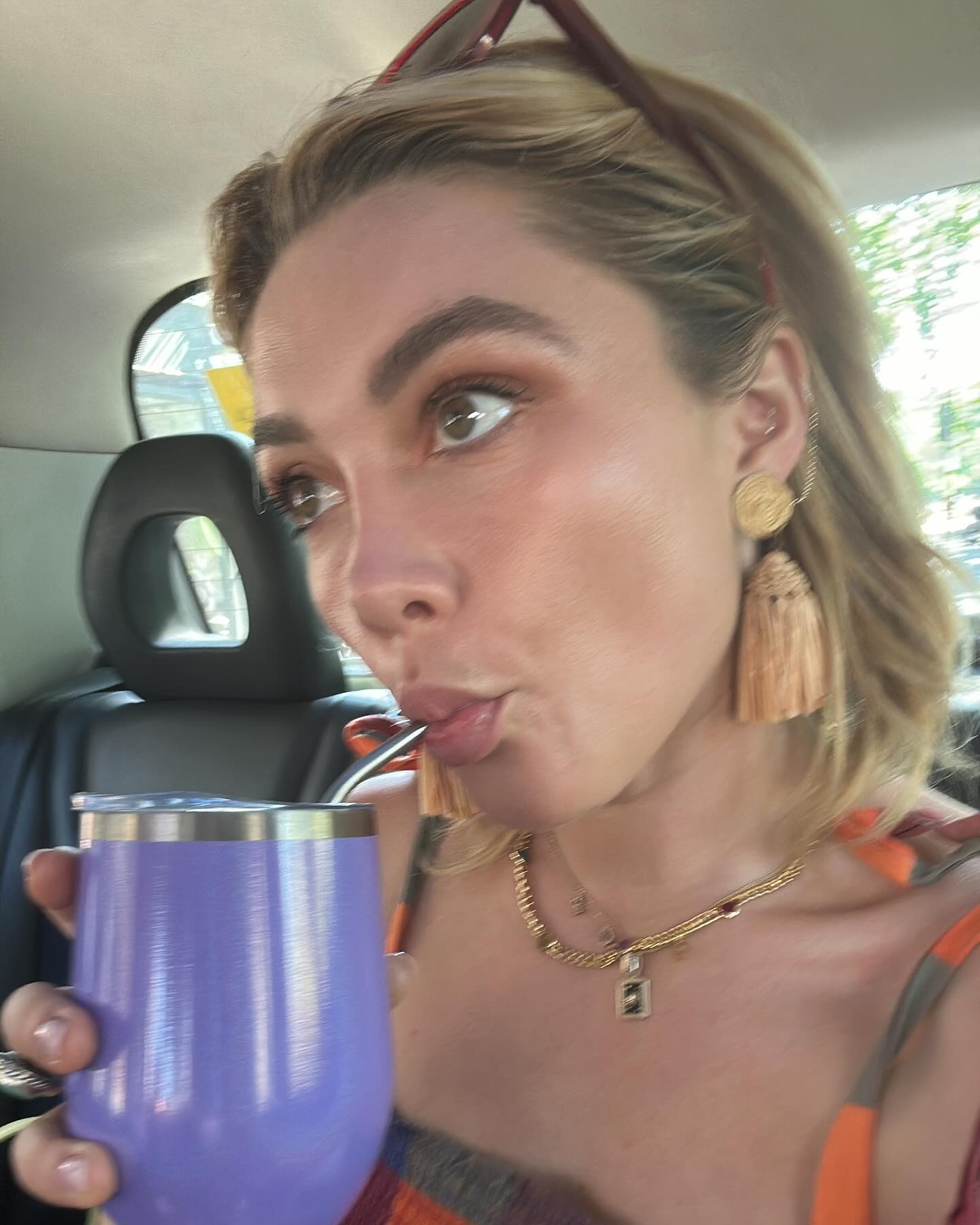 Florence Pugh in a taxi having a drink with a blonde bob hairstyle and sunglasses on her head