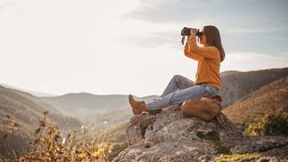 Woman using binoculars on mountain