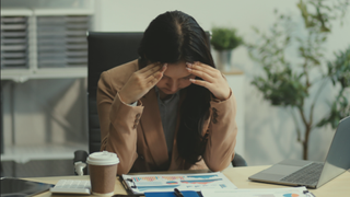 Woman looking like she has a headache while studying data charts 