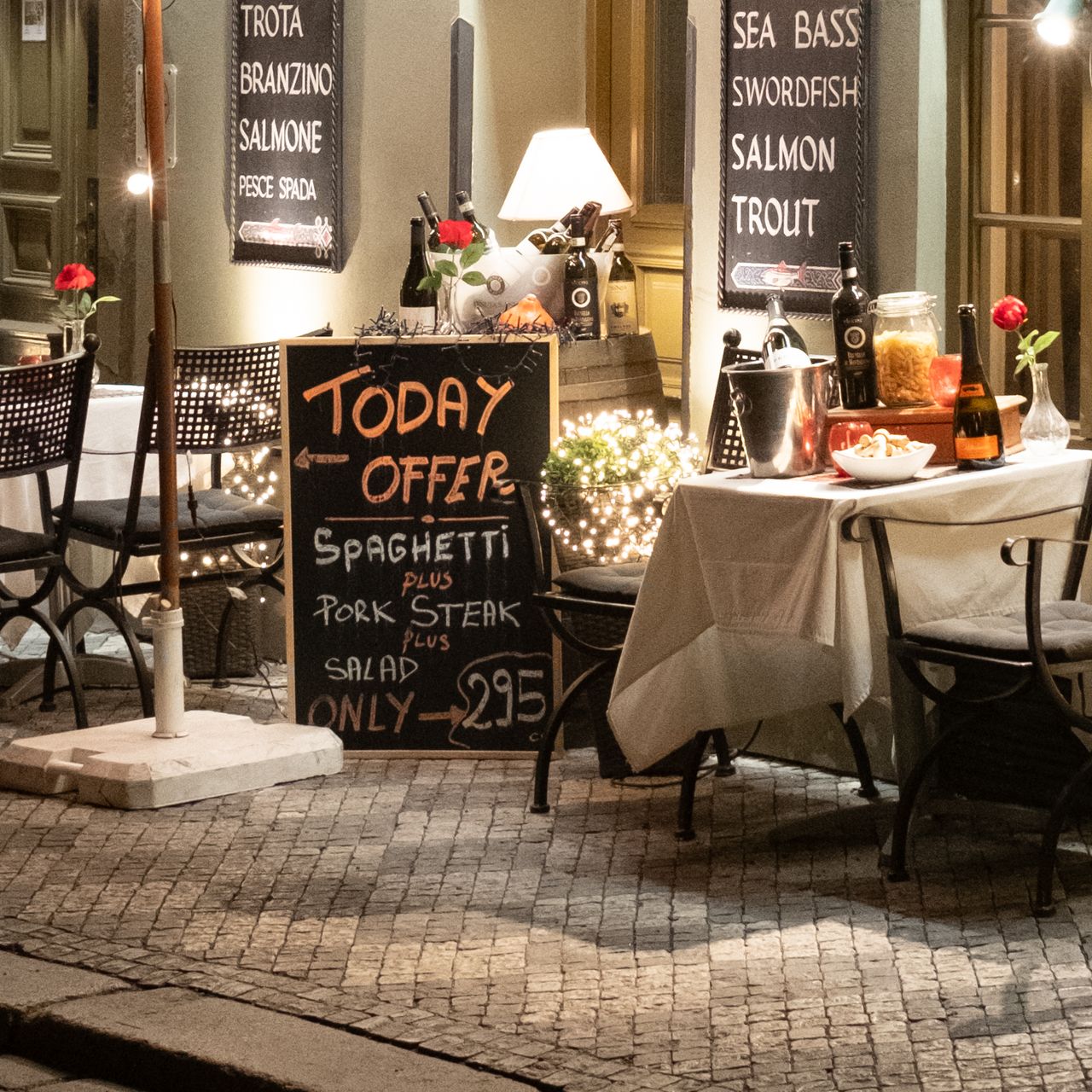 A restaurant in Prague on a cobbled street lit up at night