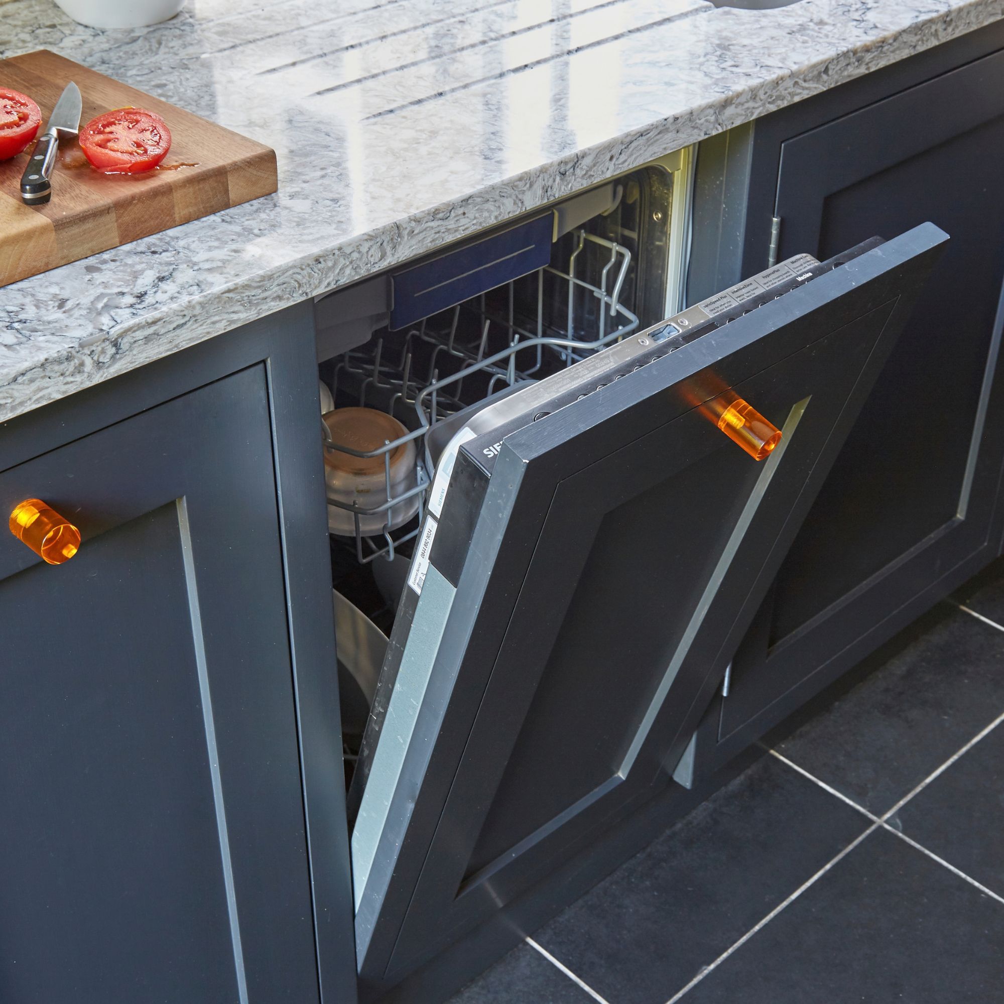 Blue kitchen cabinets with an open integrated dishwasher