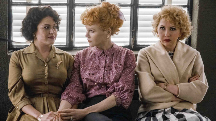 The cast of Being The Ricardos sitting on a bench
