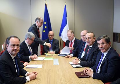 French President Francois Hollande (L) meets with Turkish Prime Minister Ahmet Davutoglu (R) and Foreign Minister Mevlut Cavusoglu (2nd R) on the second day of a European Union summit to disc